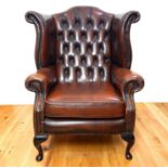 A brown buttoned leather wing back armchair