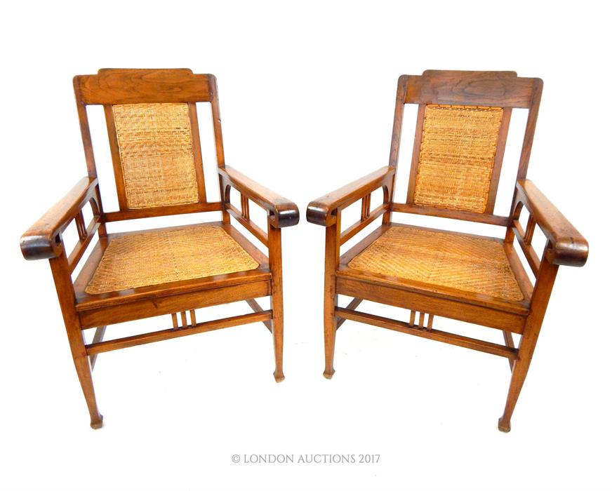 A pair of Dutch Indonesian teak chairs with rattan seats.