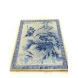 An oriental 20th century, blue and white tile featuring birds with flowers; 36cm x 25cm.