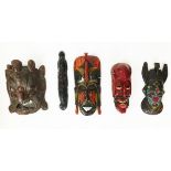 A collection of five carved wood tribal masks from southeast Asia and Africa
