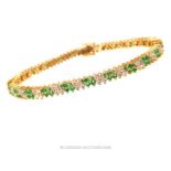 An exquisite, boxed, 14 ct yellow gold, diamond and emerald, tennis bracelet
