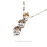 An 18 ct white gold, three-stone, champagne-coloured diamond pendant