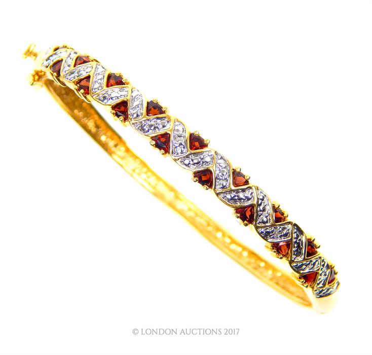 A gilt metal bangle set with garnets and white crystals