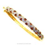 A gilt metal bangle set with garnets and white crystals