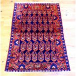 A Persian/ Kurdish rug with a navy blue and terracotta field with repeating motifs