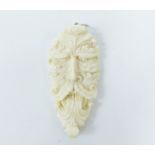 A carved bone pendant in the form of a grotesque mask