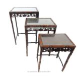 An oriental nest of three hardwood tables; a/f; with glass inserts for tops.
