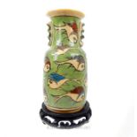 A pottery vase, hand painted with fish on a green ground