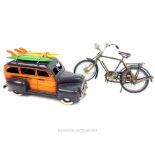 A painted model car with surf boards on the roof, together with a model bicycle
