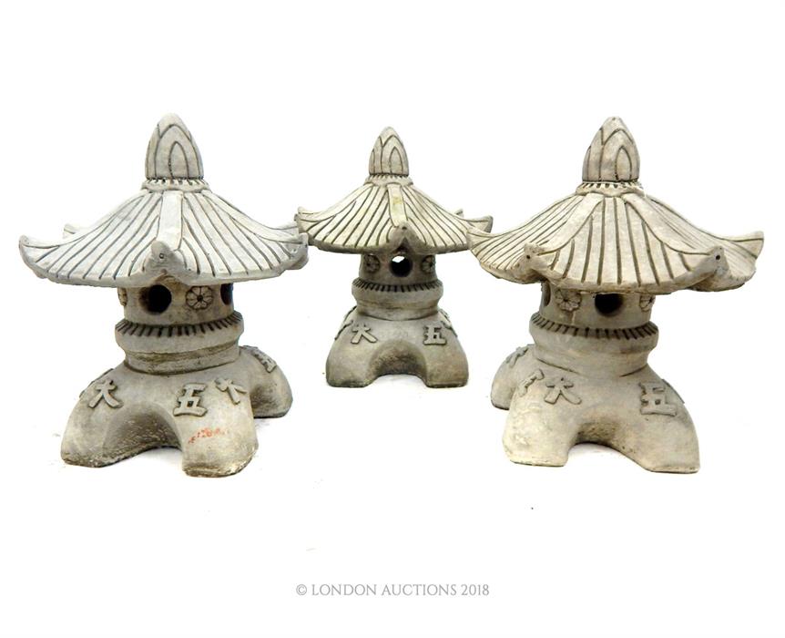 Three small composite stone ornaments with pagoda tops.