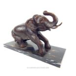 A bronzed cast metal figurine of an Elephant raised upon a marble base.