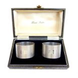 A pair of cased sterling silver napkin rings retailed by Harrods