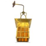 A brass wall mounting hanging lantern with a square textured amber glass shade