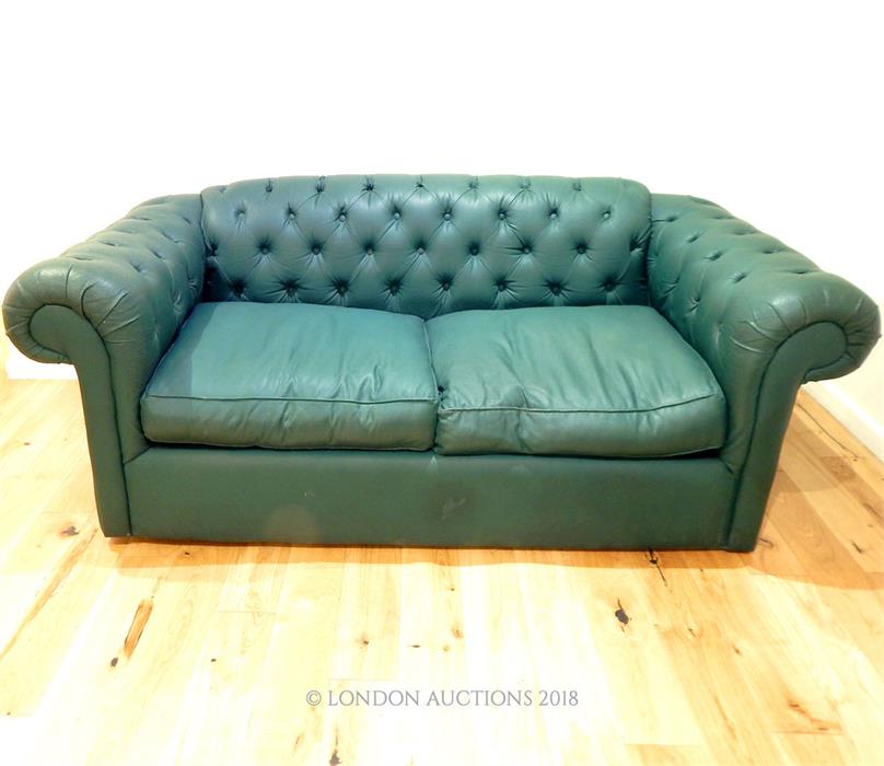 A dark green leatherette, Chesterfield-style sofa bed