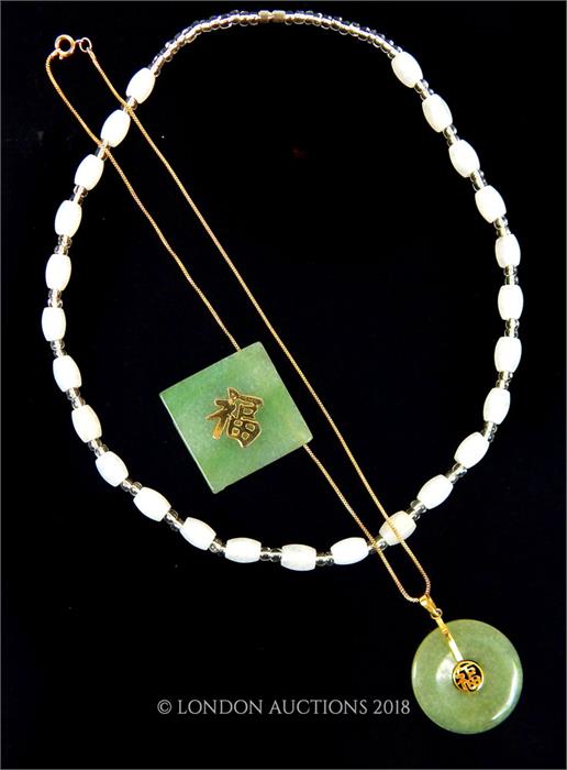 A Chinese green jade pendant with another together with a white stone necklace.
