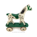 A mid 20th century wooden horse, hand painted and upon tin wheels; 50cm long.
