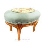 A teal, upholstered foot stool with a carved frame