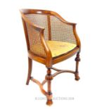 An early 20th century walnut and caned tub chair