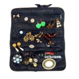 A black satin jewellery roll containing numerous pairs of earrings