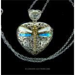 A sterling silver, heart-shaped locket with dragonfly detail on silver chain