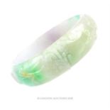 A carved, Chinese jade bangle in shades of green and violet