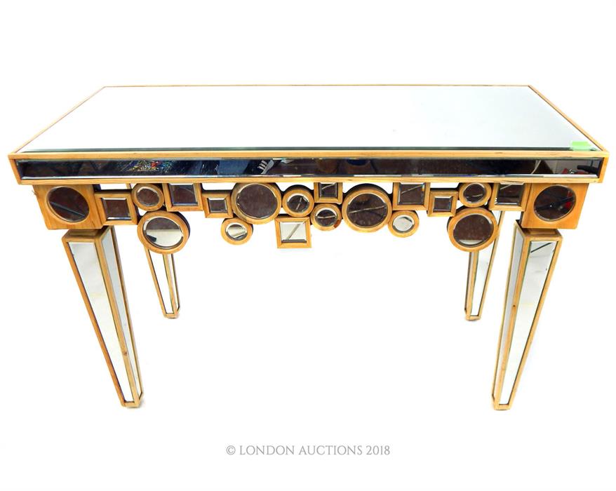 A contemporary console table formed of bevelled mirrored panels