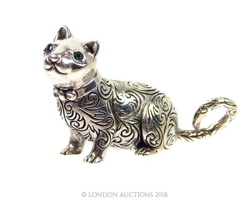 A cast silver figure of a cat with emerald eyes.