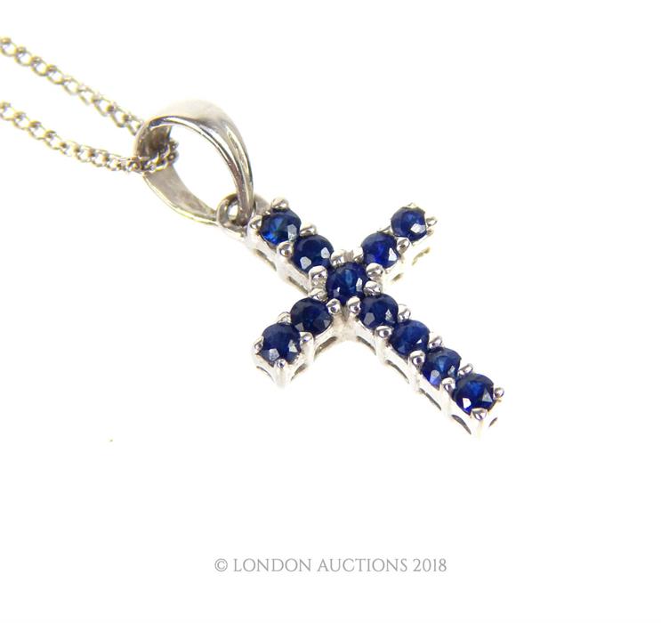 A 9 ct white gold and sapphire cross pendant on a 9 ct white gold chain