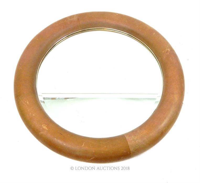 A large circular mirror with leather frame