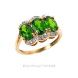 A 14ct yellow gold ring with three green garnets surrounded by diamonds