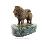 A silvered sculpture of a Chow dog on a green marble base