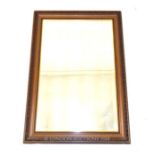 A rectangular framed wall mirror with a bevelled plate