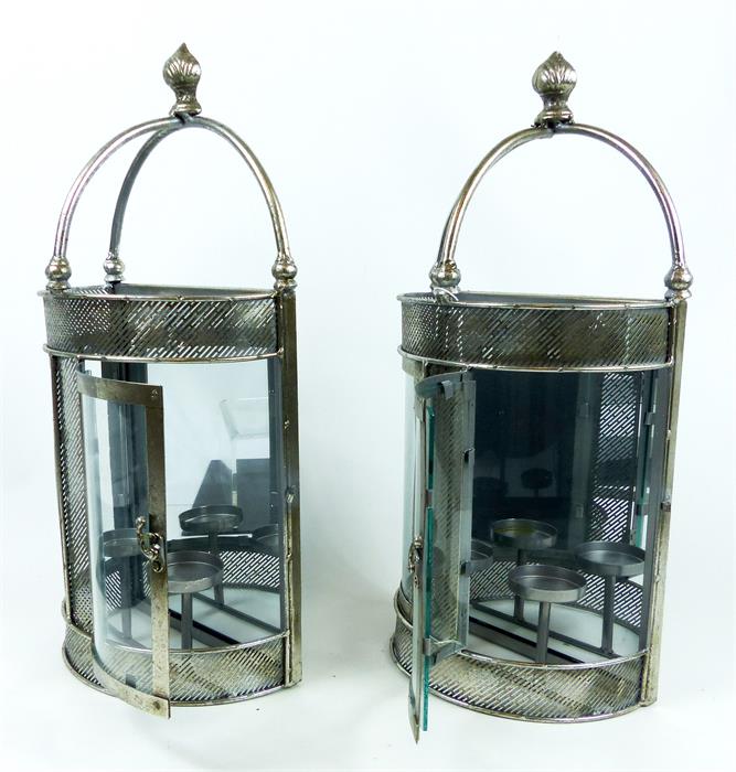 A pair of chromed, wall-mounted, candle holders