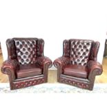 A pair of burgundy leather button back armchairs