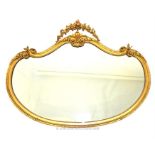 A Victorian wall mirror in a swept gilt plaster frame