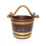 An oak and brass bound coopered bucket with a rope handle