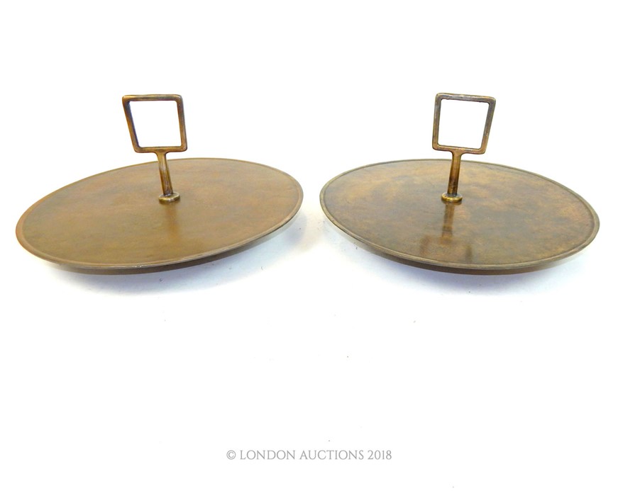 A pair of circular bronze trays with handles