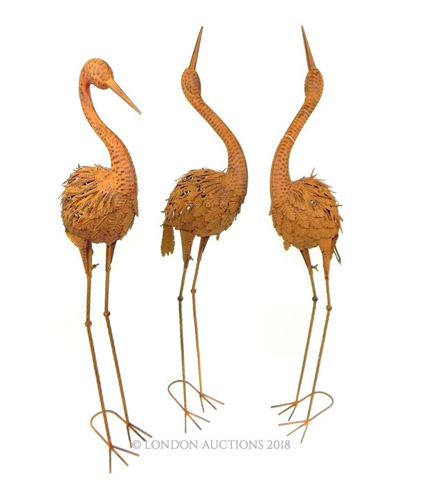 A set of three painted and distressed metal figures of cranes