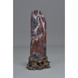 A Chinese red colour stone ornament fitted on a carved wooden stand. 20cm tall with stand