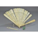 A Chinese ivory fan (damaged) together with a carved jade stone mounted in a silver colour ring. (2)