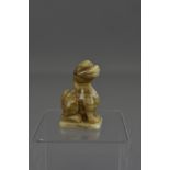 A Chinese carved celadon jade figure of a seated dog. 8cm tall