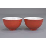 A pair of Chinese 20th century or earlier ruby-red glazed porcelain tea cups with incised decoration