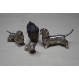 A group of three cast metal figures depicting dachshunds and a cold painted basset hound.