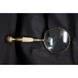 A large hand held magnifying glass decorated with mother of pearl.