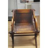 A late 19th Century/early 20th Century oak ecclesiastical canterbury type elbow chair.