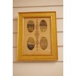 An assortment of framed and glazed needlework textiles.