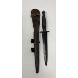 A WWII third pattern Commando knife in its original leather scabbard with metal mounts.