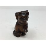 A Japanese carved wooden netsuke in the form of a dog carrying a barrel.