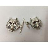 A pair of silver cufflinks in the form of wolves' heads.