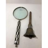 A large hand held magnifying glass and a vintage hand held bell.